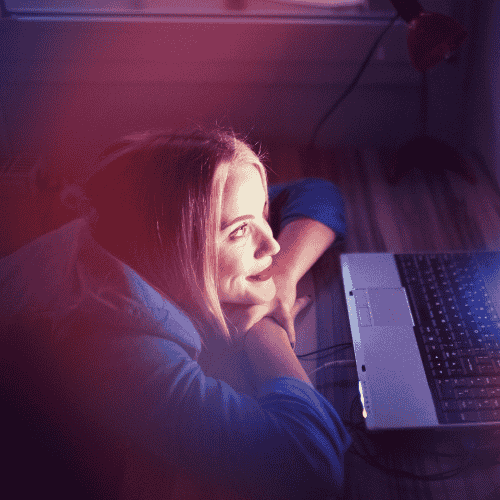 Woman laid on bed looking at laptop