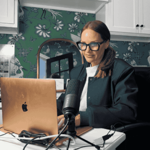 Erica Suzanne Fultz sat in home office at a desk with an apple mac and microphone set up on the desk
