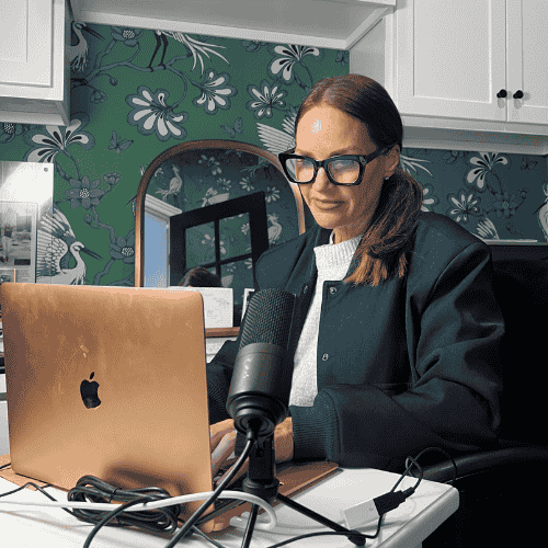 Erica Suzanne Fultz sat in home office at a desk with an apple mac and microphone set up on the desk