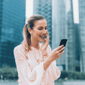Professional woman wearing a pink blouse whilst holding phone and giggling