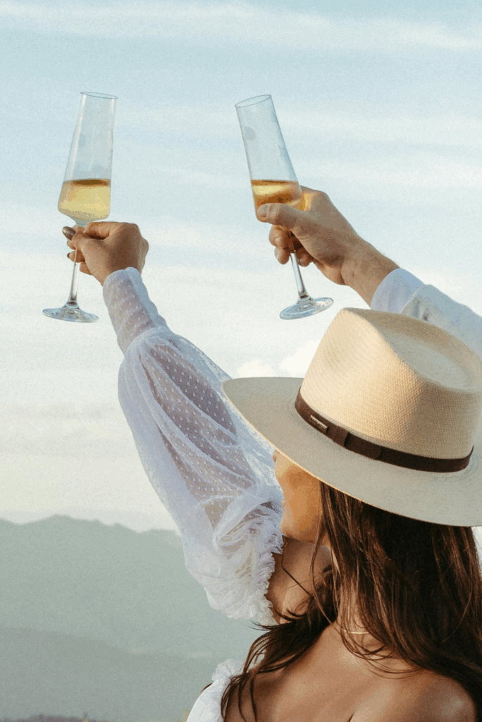 Woman toasting with champagne wearing a straw hat.