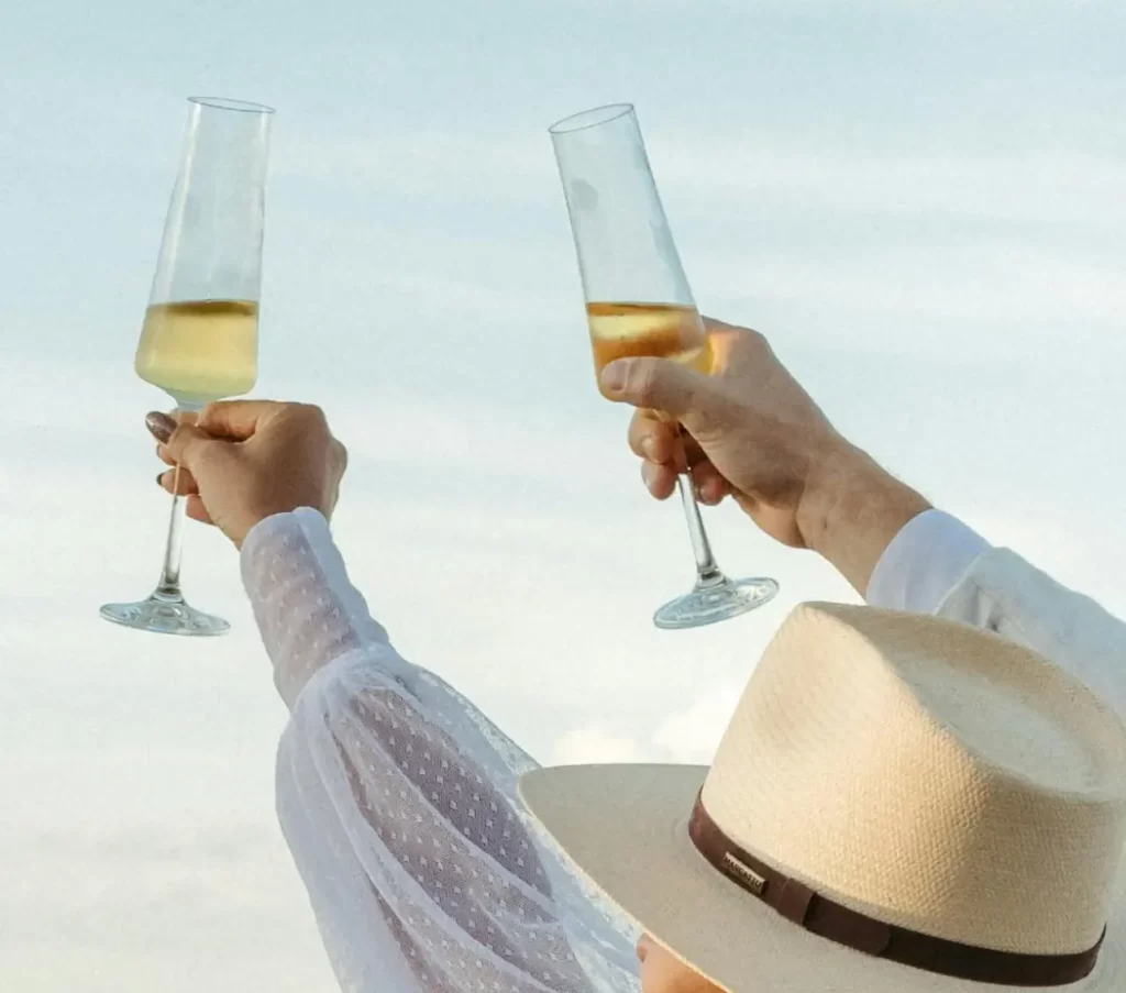 Woman toasting with champagne wearing a straw hat.