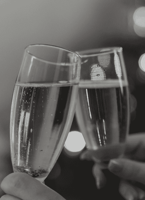 Black and white photo of two champagne flutes being used to toast