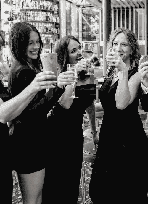 Black and white photo of Erica Suzanne Matchmaking team toasting with champagne flutes