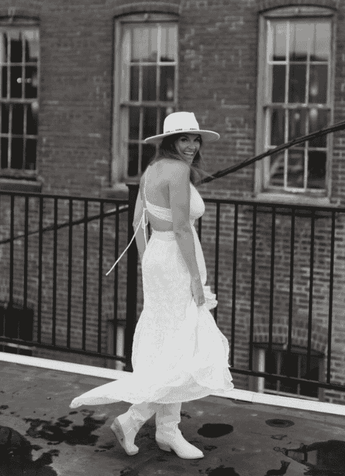 Black and white photo of Erica Suzanne Matchmaking in a white dress wearing a cowboy hat.